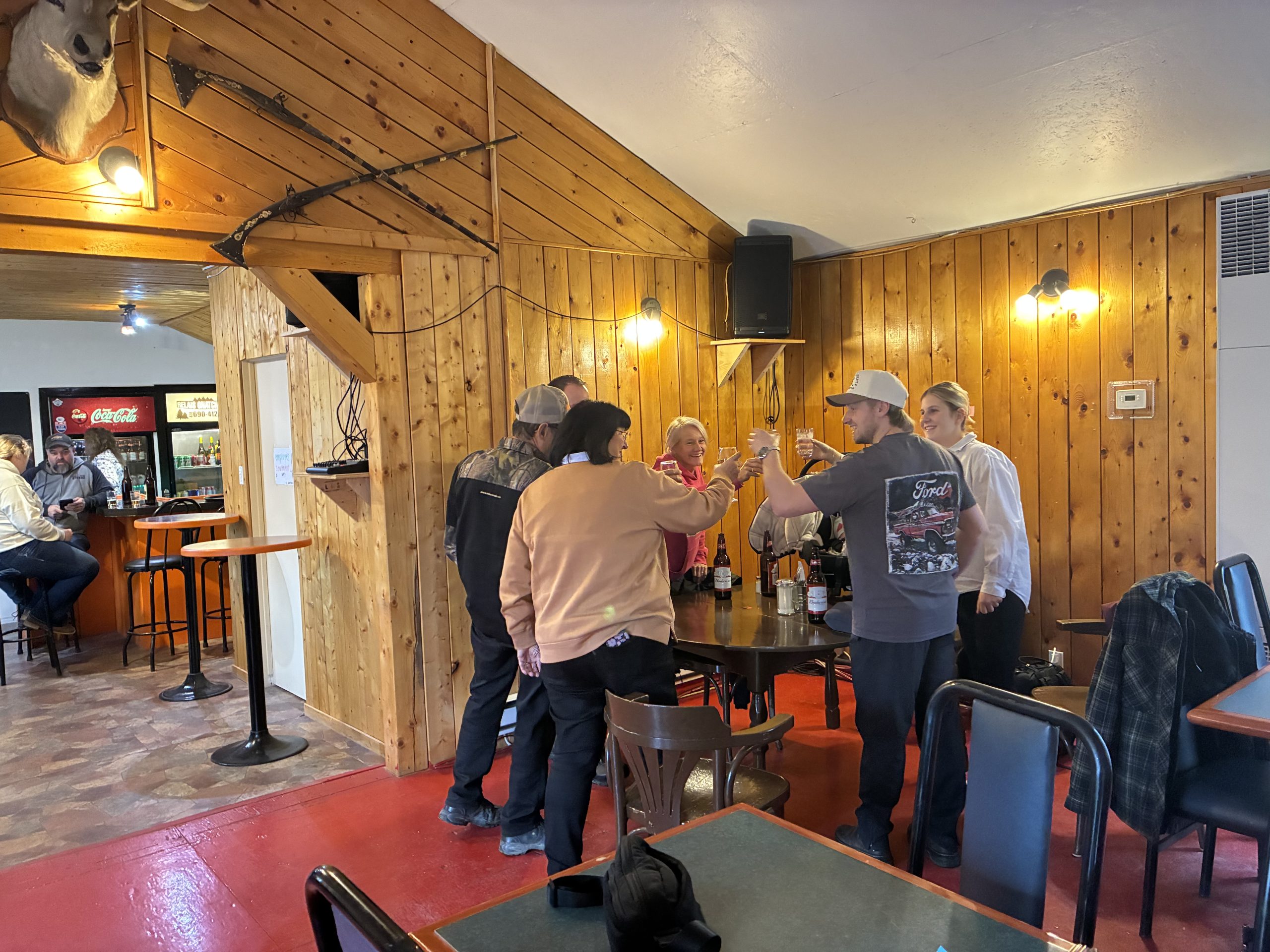 Intérieur du restaurant du Relais Onatchiway avec des clients qui trinquent à une table