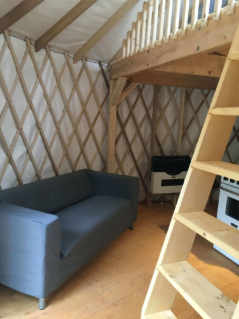 Interieur de la yourte au Relais Onatchiway - sofa, echelle et cuisinette
